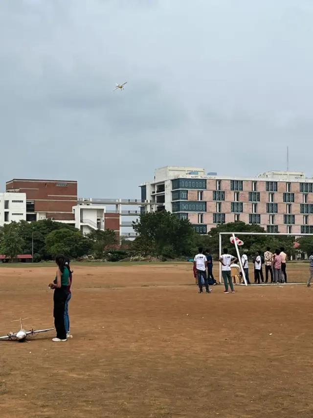 The cargo plane small in the sky above the playing field, a pilot at the controls in the foreground